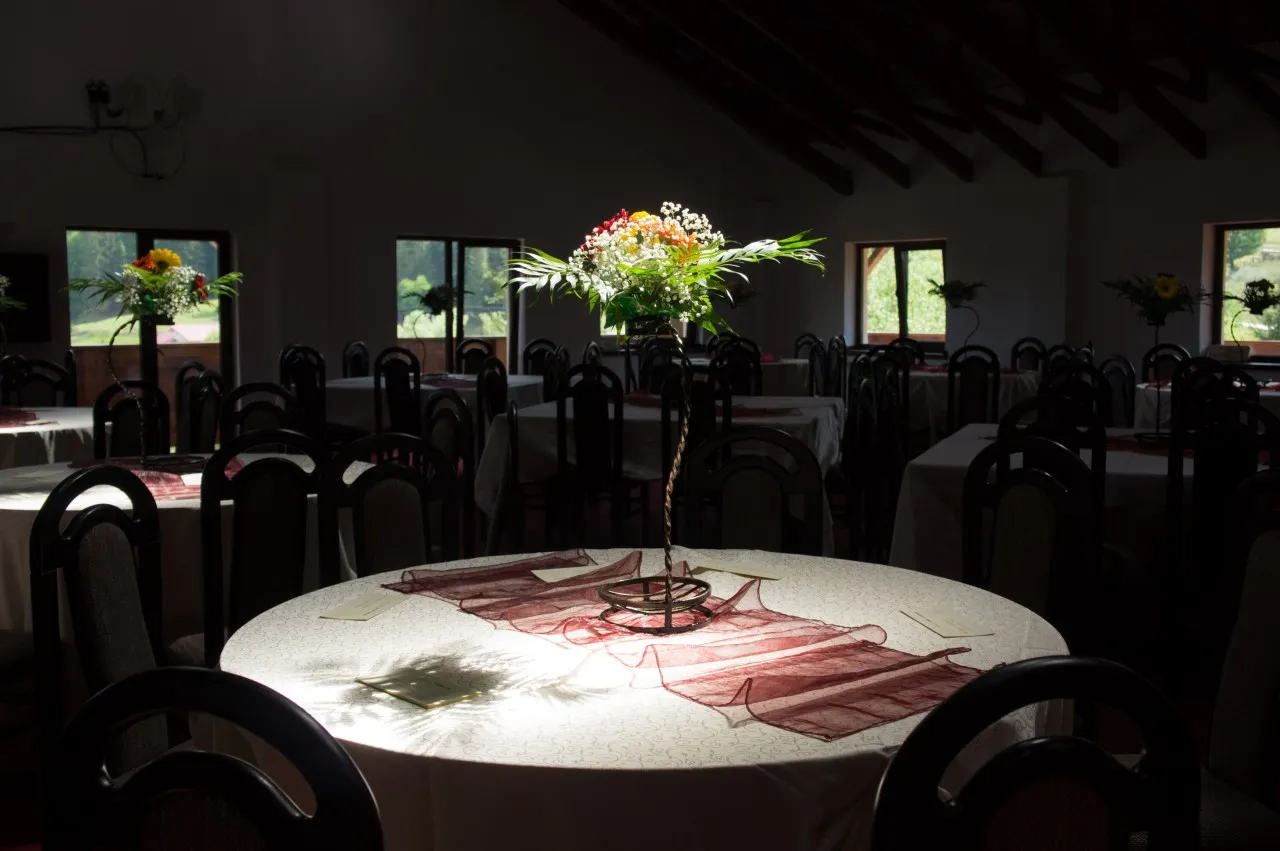 A round table laid, with a tall flower arrangement in the middle.