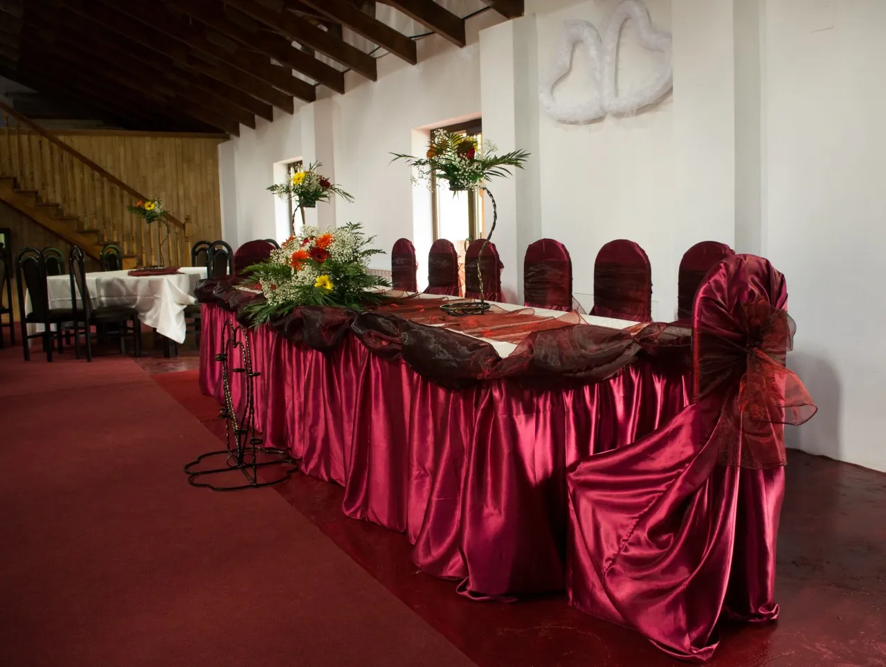 The long top table, dressed in burgundy satin, with flower arrangements and covered chairs.
