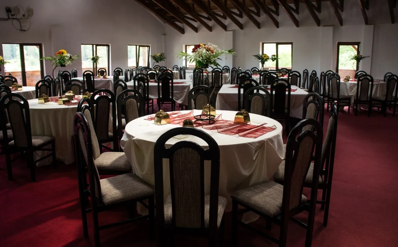 The events hall, with round tables laid and a flower arrangement on each.