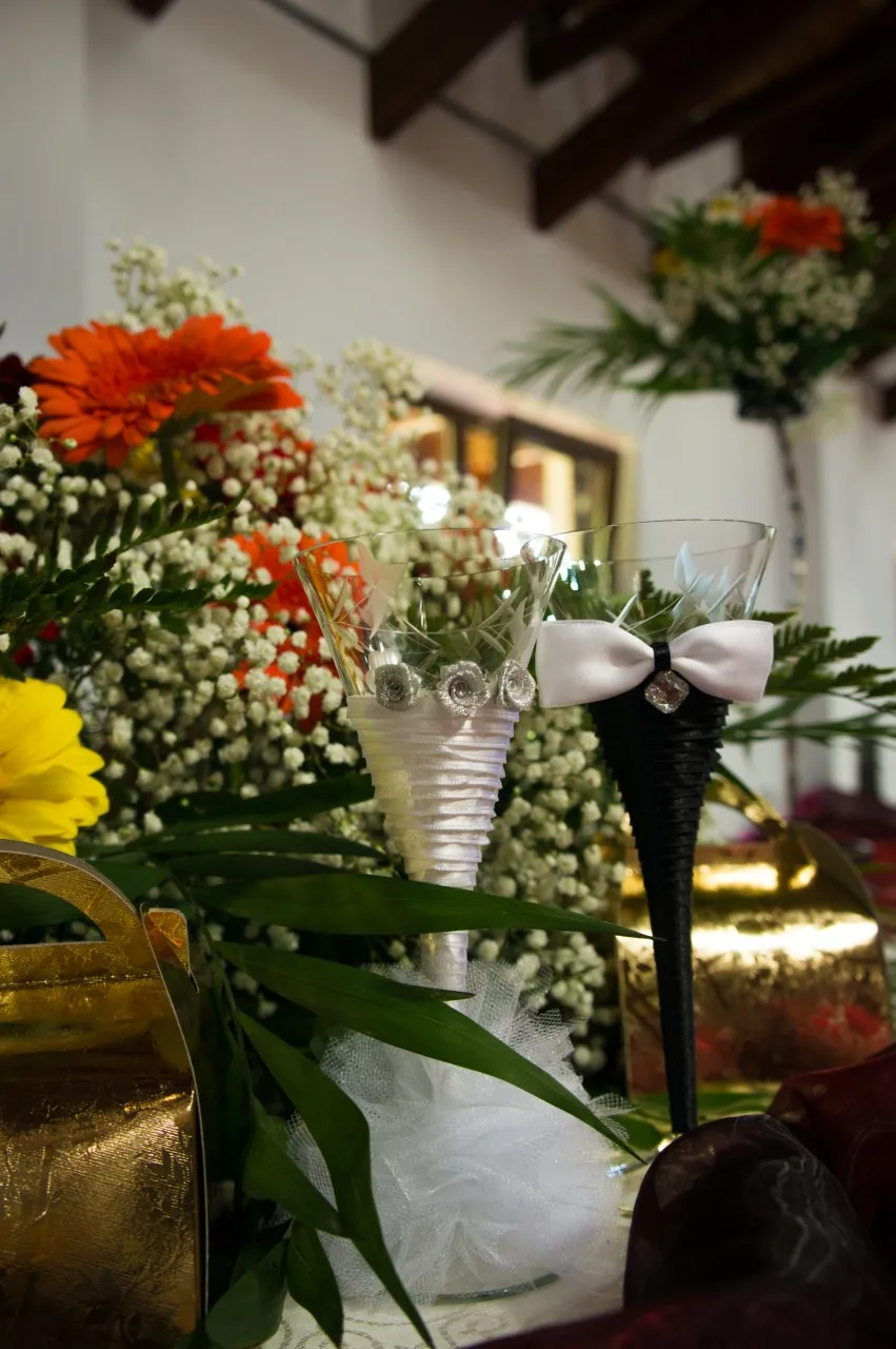 Glasses tied with white ribbon, in front of a flower arrangement of gerberas.