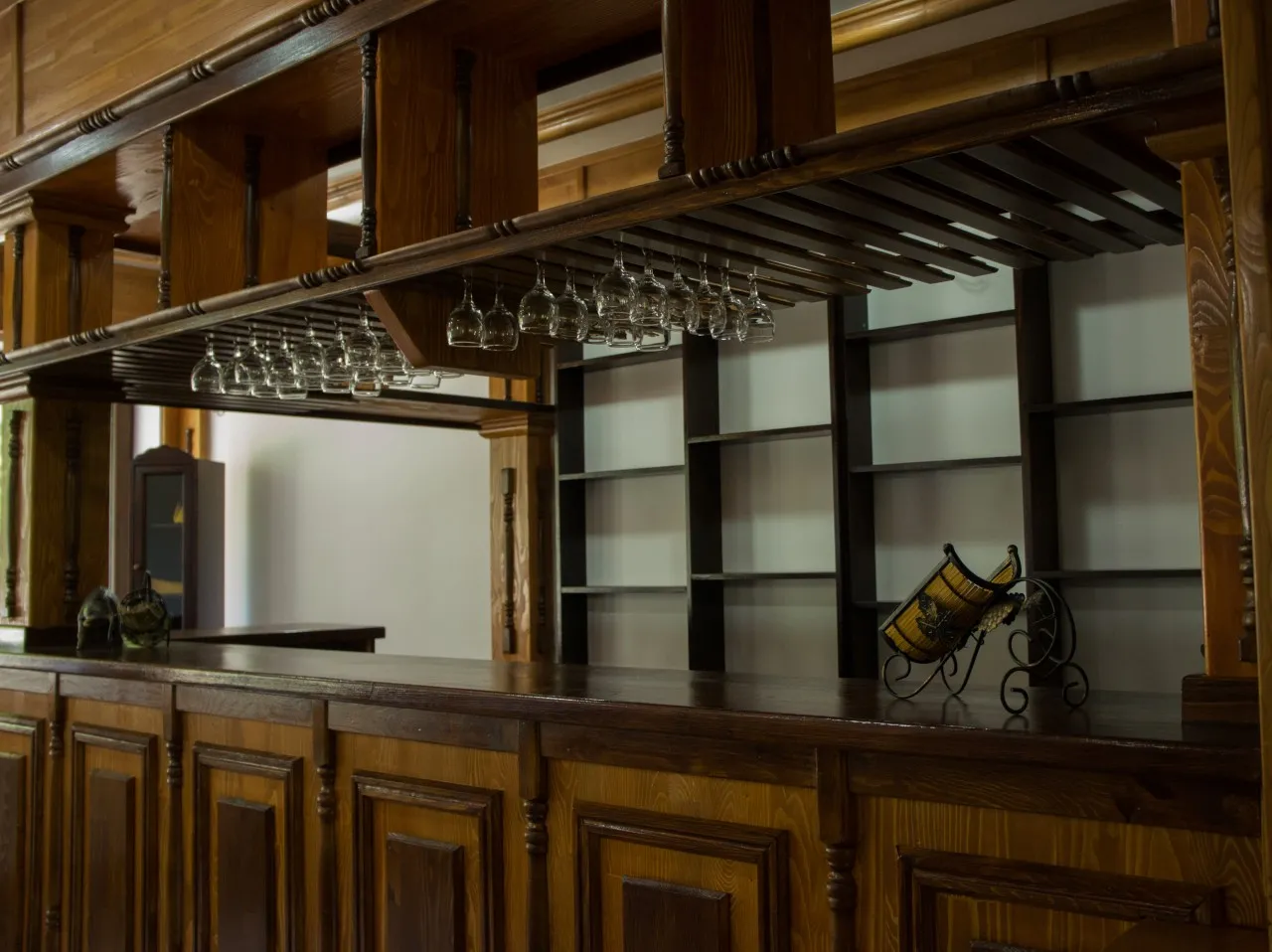 The chalet's bar, with a dark wooden counter and shelves and glasses hanging above it.