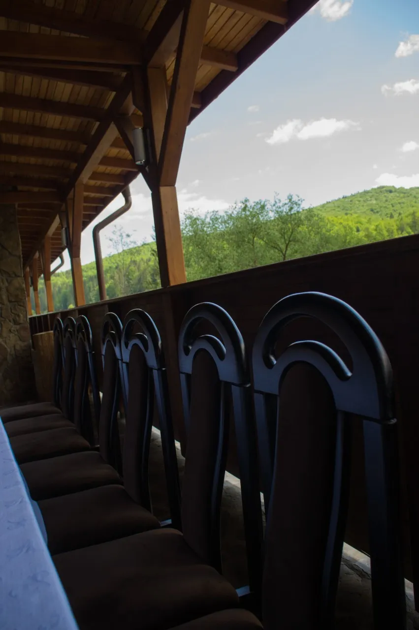 The long covered terrace, with chairs lined up along the railing and green hills behind.