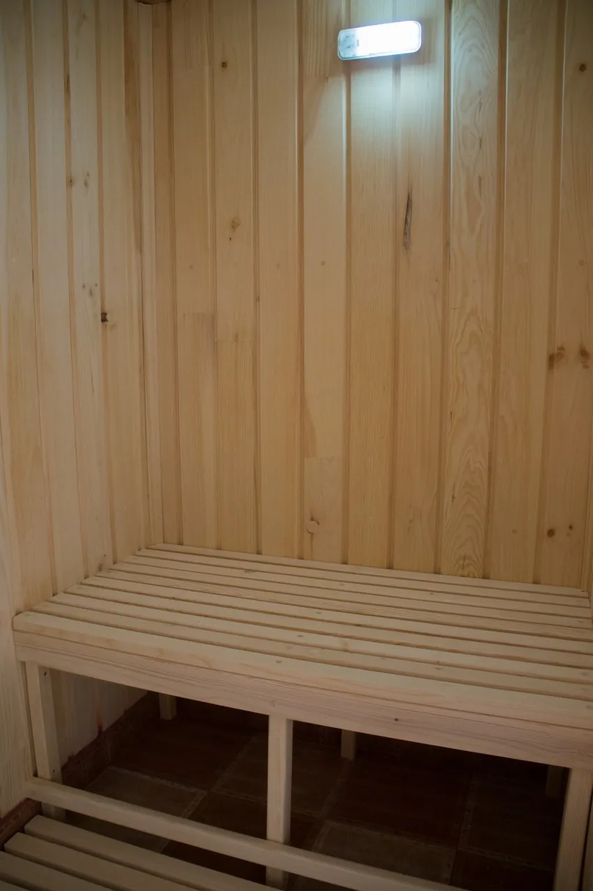 The inside of a pale wooden sauna, with a long bench and plank walls.