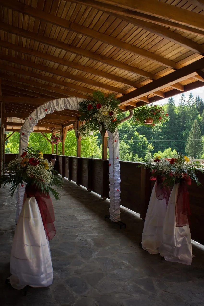 The chalet's covered terrace decorated for a wedding, with an arch of flowers and white voile between the wooden posts.