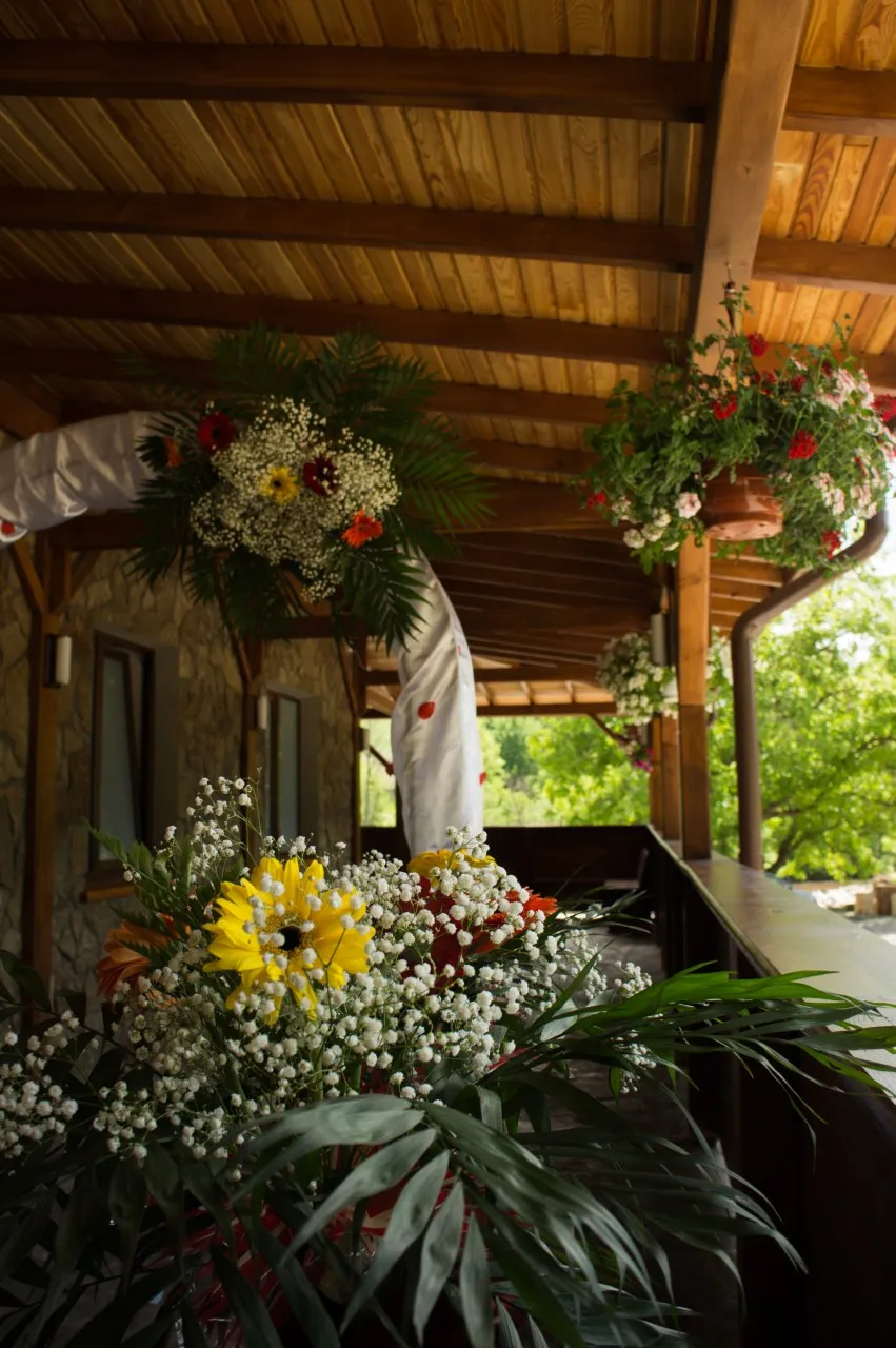 The terrace dressed for a wedding, with flower arrangements and white voile between the wooden posts.